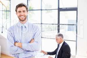 Smiling businessman crossing arms in front of working businessma