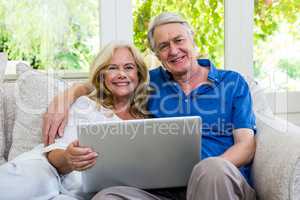 Portrait of happy senior couple with laptop at home