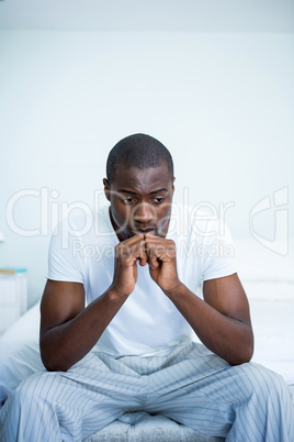 Tensed young man sitting on bed