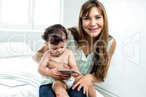 Happy mother with son holding cellphone on bed