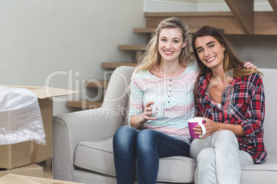 Two beautiful women sitting side by side with a mug of coffee