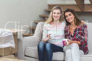 Two beautiful women sitting side by side with a mug of coffee