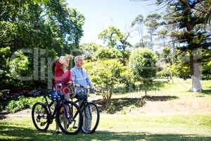Senior couple walking with bicycle in park