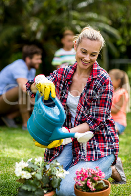 Woman watering flowers on grass at yard