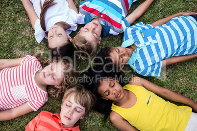 Children lying on grass with eyes closed