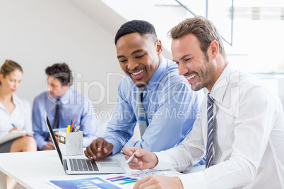 Businessmen reviewing a statistical report at desk