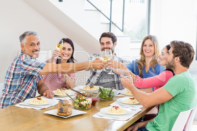 Friends toasting wine glasses while having a meal