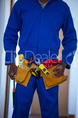 Mid section of handy man wearing tool belt