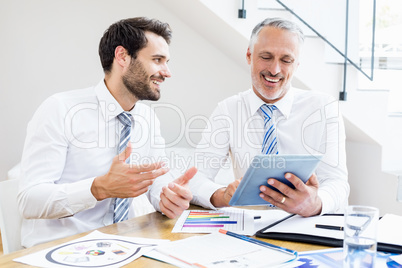 Businessmen discussing office work on digital tablet