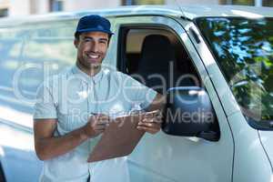 Portrait of smart delivery man writing in clipboard