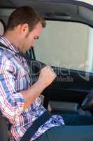 Young man putting on his seat belt