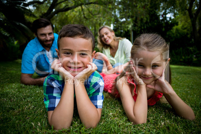 Children lying with head in hands against parents  in yard