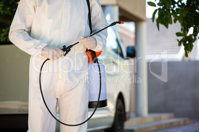 Mid section of pest control man standing next to a van