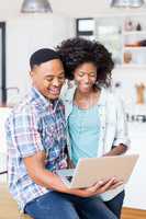 Happy young couple using laptop in kitchen