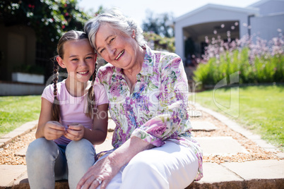 Grandmother and granddaughter sitting in the garden