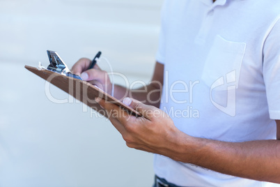Midsection of delivery man writing in clipboard