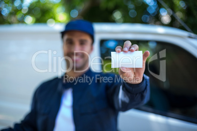 Smiling delivery man showing business card