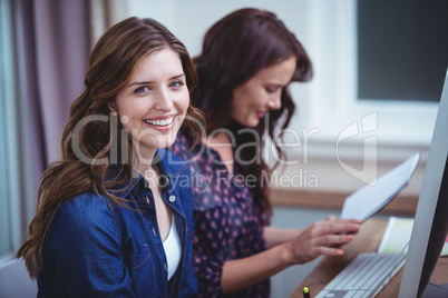 Portrait of two women sitting in front of computer