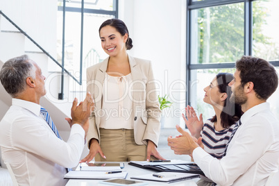 A businesswoman is standing in front of her colleagues who are a