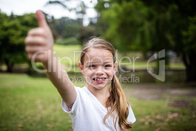 Happy girl showing her thumbs up in the park