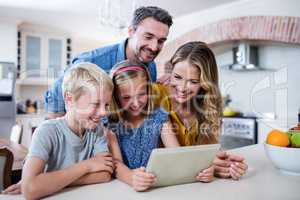 Parents and kids using digital tablet in kitchen