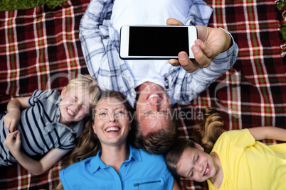 Happy family taking a selfie while lying in the park