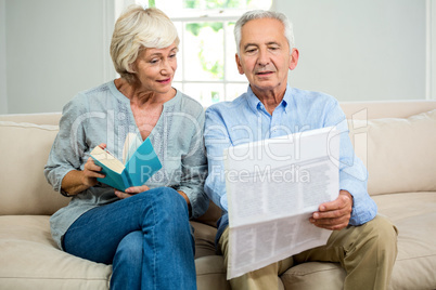 Senior couple reading newspaper at home