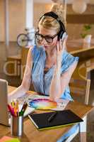 Graphic designer listening to headphones while using laptop