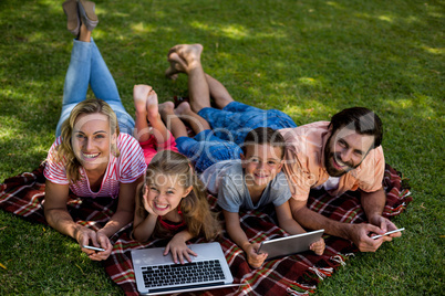 Smiling family using technologies while lying in yard