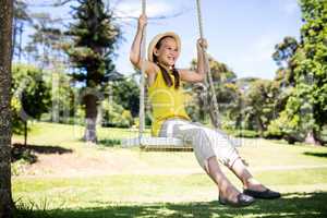 Happy girl sitting on a swing in the park