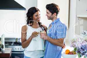 Young couple toasting glasses of wine in kitchen