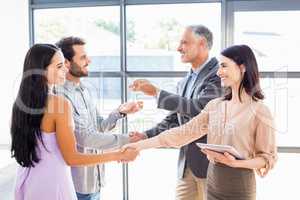 Real estate agent handing over house key to young couple