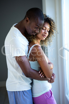 Young couple embracing near window