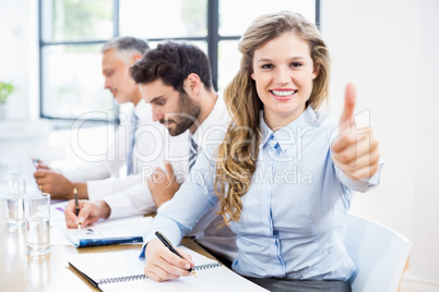 Portrait of businesswoman showing thumbs up