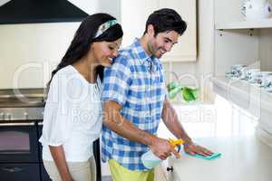 Happy woman looking while man cleaning the kitchen