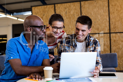 Colleagues interact using laptop at desk