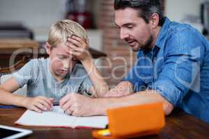 Father helping son with his homework in kitchen