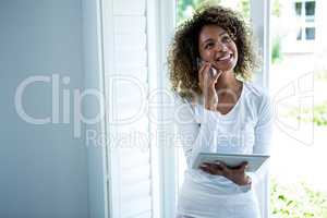 Woman talking on the phone while using the digital tablet