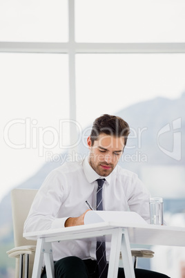 Businessman using laptop and taking notes