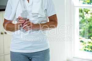 Mid section of senior woman standing with water bottle