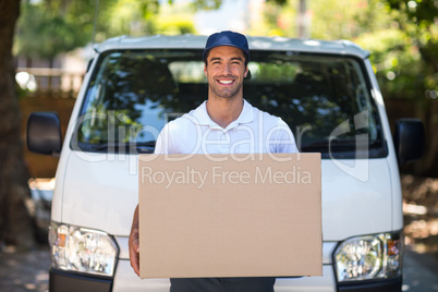 Portrait of smiling delivery person holding cardboard box
