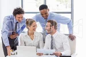 Happy business colleagues reviewing a report at desk