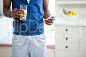 Mid- section of man holding a glass of juice while text messagin