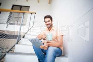 Man holding digital tablet and coffee mug