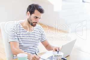 Man writing note using laptop