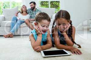 Children watching digital tablet screen while parents in backgro