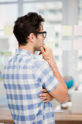 Thoughtful man looking at sticky notes on window