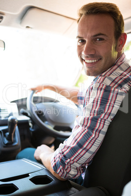 Young man looking at camera while sitting on cars front seat