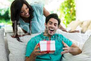 Woman giving a surprise gift to man
