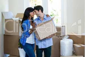Young couple standing face to face while carrying cardboard box